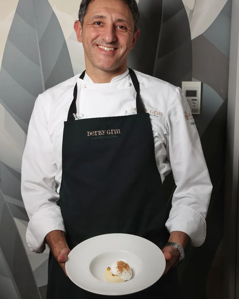 Fabio Silva sorridente, con il grembiule del Derby Grill, tiene in mano il suo dessert