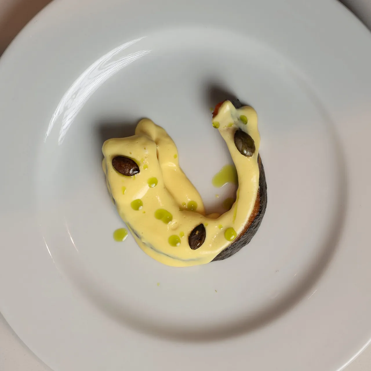 Zucca Delica e provola affumicata di Giuseppe Silvestro: spicchio di zucca con crema gialla e semi, in un piatto bianco